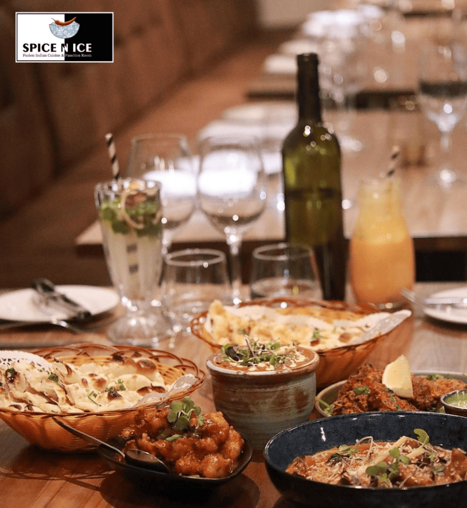 A table filled with Indian catering dishes like biryani, butter chicken, and naan