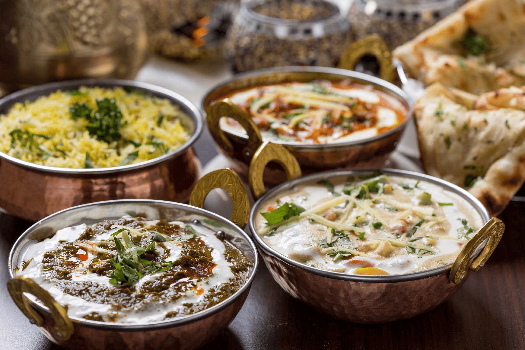 Colourful array of traditional North Indian dishes including curry, naan, and rice.